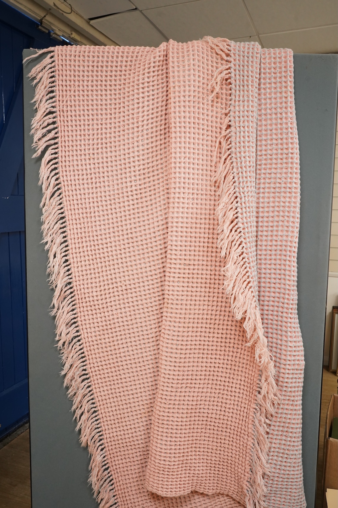 A pink and grey Welsh blanket with tasseled edges
